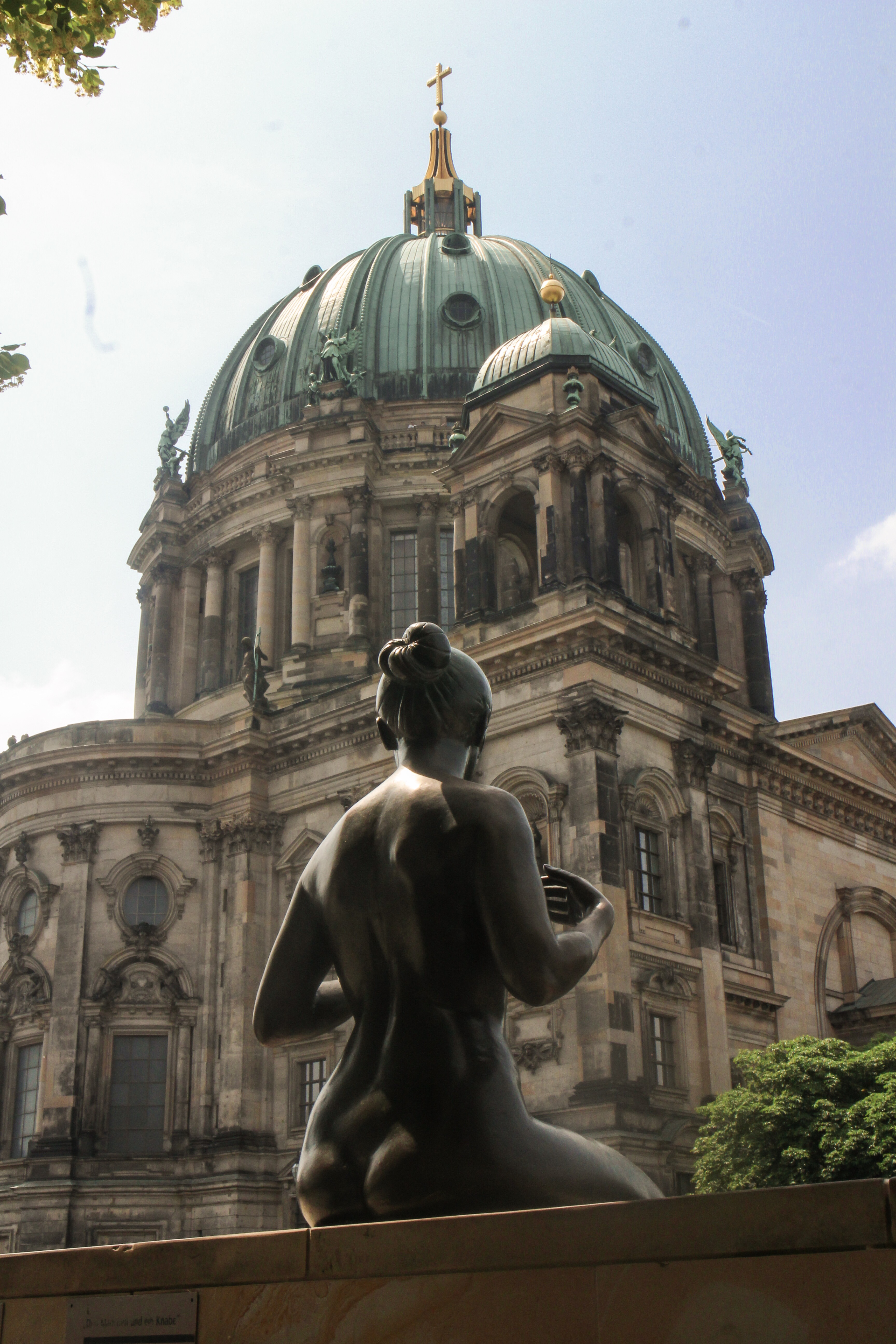 A statue of a girl looking aross the River Spree at the Berlin Cathedral