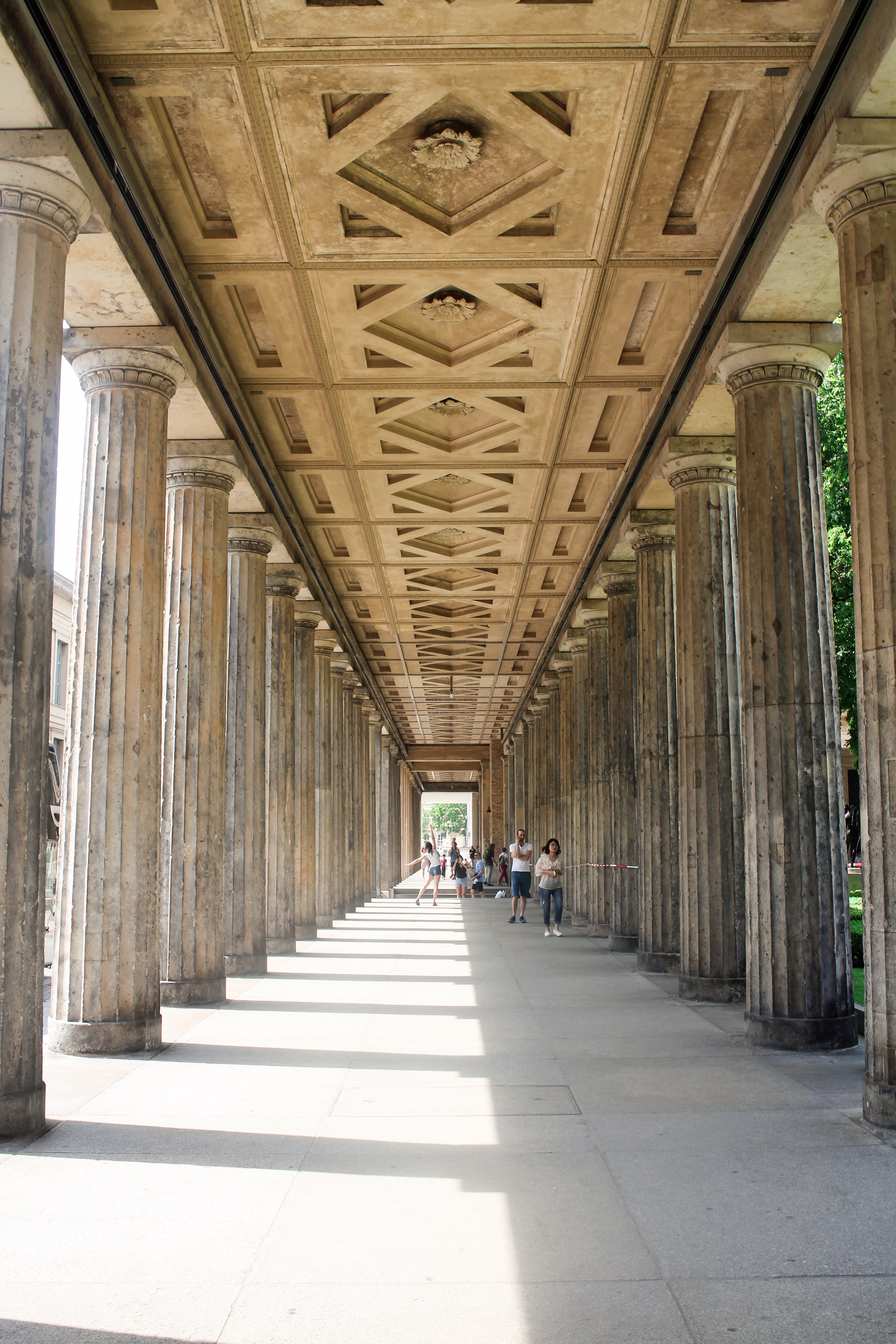 a stone walkway with pillars and a decorative ceiling