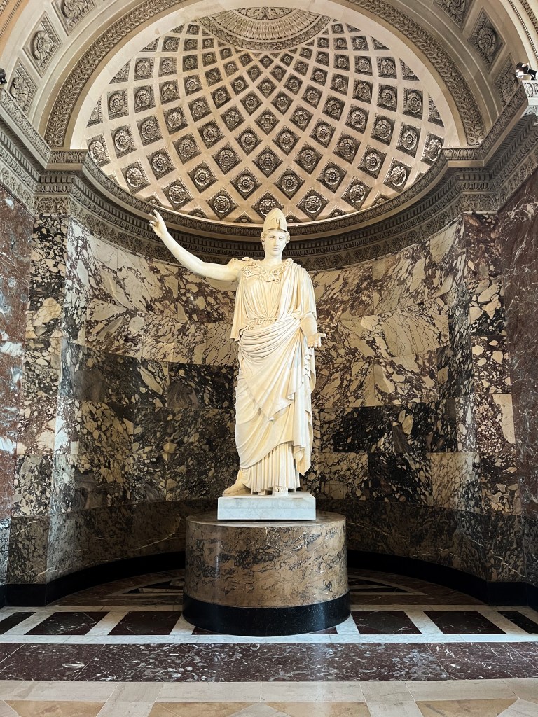 a roman statue situated in a beautiful marble alcove with different colours and patterns of stone