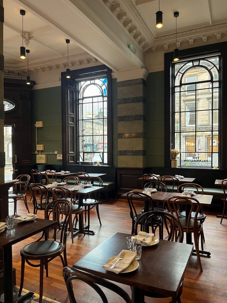 an empty restaurant ready for the lunch service. the large windows let lots of light into the dining room