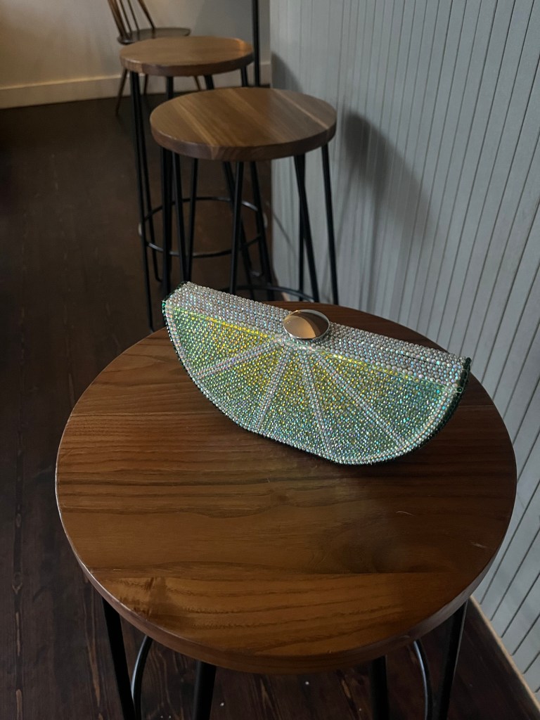 A sparkly clutch bag, designed to look like a lime wedge perched on a bar stool.