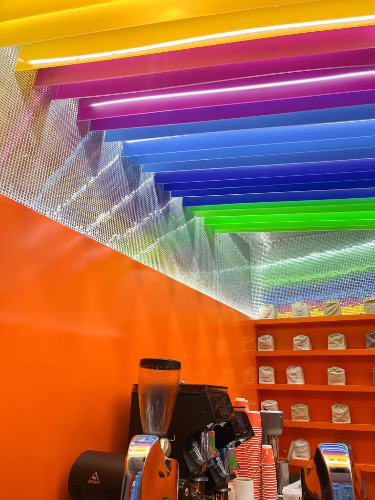the rainbow coloured ceiing of a coffee shop with surrounding disco tiled and orange painted walls