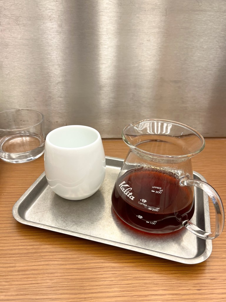 a coffee jug and cup sit on a metal tray