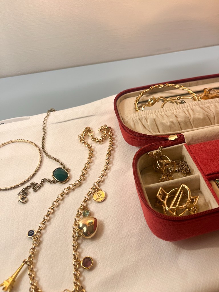 a small jewellery box opened with golden necklaces and bracelets spilling out