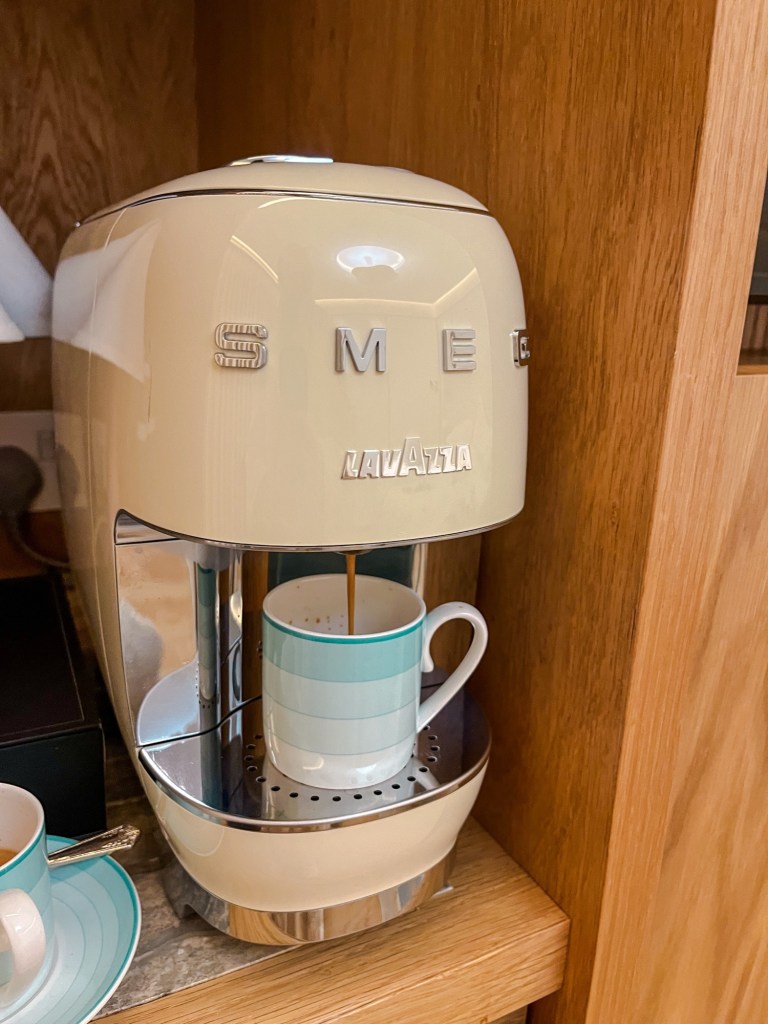 a little beige coffee pod machine pouring espresso into a turquoise Claridge's cup