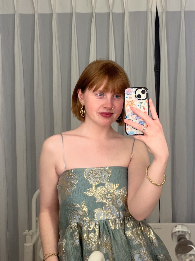 a mirror selfie taken by a redheaded girl in a shimmery, embroidered Sister Jane dress