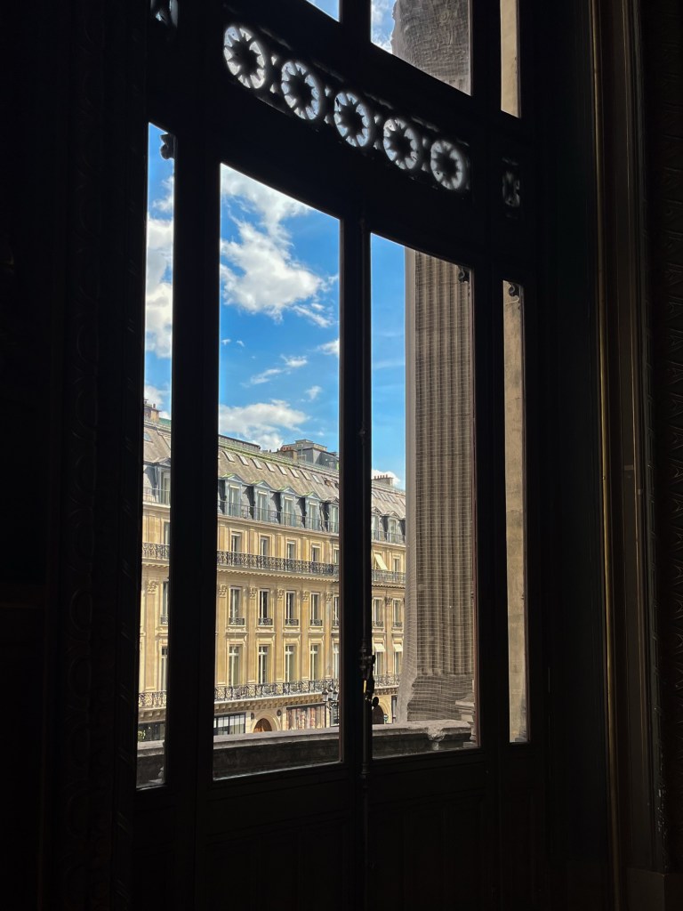 a glimpse of Parisian architecture through a darkened window