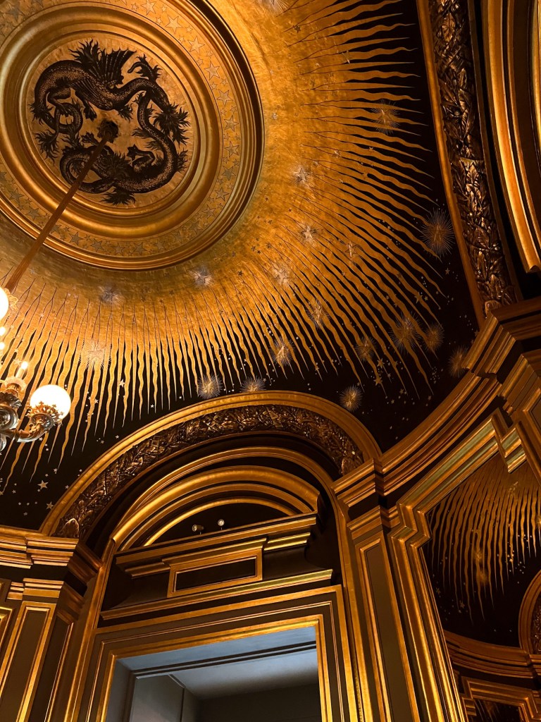 a small, dark, round room that has a gold ceiling painted to look like the sun