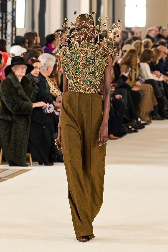 A gold sculptured bodice covering the model's face with jewel tones