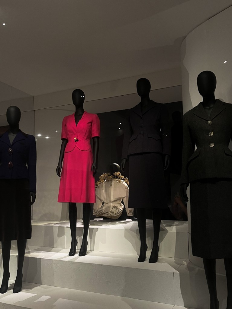 a collection of suits; all black except one in shocking pink