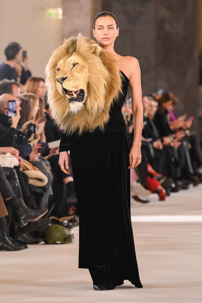 A black column dress with one sleeve and a lion's head protruding from the shoulder